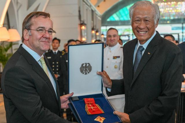 Germany's Defence Minister Boris Pistorius (L) presents the Federal Cross of Merit of Germany to Singapore's former Defence Minister Ng Eng Hen (R) in Singapore on March 24, 2026. (Photo by Roslan RAHMAN / AFP)