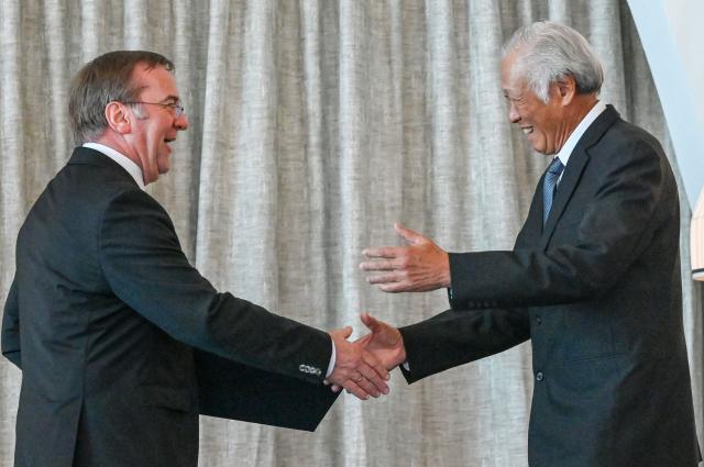 Germany's Defence Minister Boris Pistorius (L) shakes hands with Singapore's former Defence Minister Ng Eng Hen (R) before presenting him with the Federal Cross of Merit of Germany in Singapore on March 24, 2026. (Photo by Roslan RAHMAN / AFP)