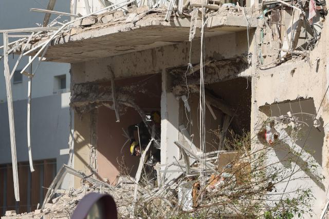 Israeli emergency service personnel inspect a building damaged in an Iranian missile strike in Tel Aviv on March 24, 2026. Iran launched a new wave of missiles against Israel on March 24, hours after US President Donald Trump hailed "very good" talks to end the war despite Tehran denying any dialogue had taken place. (Photo by Jack GUEZ / AFP) / 