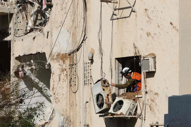 Israeli emergency service personnel inspect a building damaged in an Iranian missile strike in Tel Aviv on March 24, 2026. Iran launched a new wave of missiles against Israel on March 24, hours after US President Donald Trump hailed "very good" talks to end the war despite Tehran denying any dialogue had taken place. (Photo by Jack GUEZ / AFP) / 