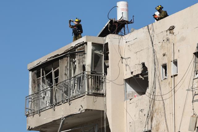 Israeli emergency service personnel inspect a building damaged in an Iranian missile strike in Tel Aviv on March 24, 2026. Iran launched a new wave of missiles against Israel on March 24, hours after US President Donald Trump hailed "very good" talks to end the war despite Tehran denying any dialogue had taken place. (Photo by Jack GUEZ / AFP) / 