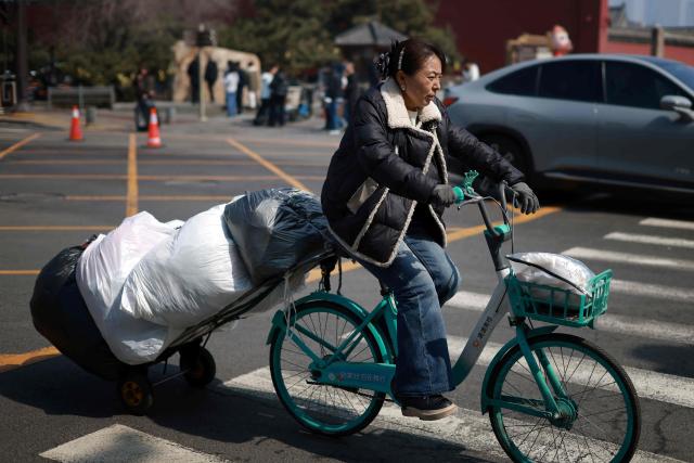 A woman rides a bicycle carrying goods in Shenyang, northern China's Liaoning province on March 23, 2026. (Photo by CN-STR / AFP) / China OUT