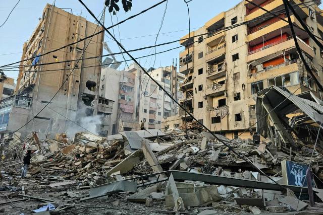 People look at debris at the site of an overnight Israeli airstrike in Beirut's southern suburb of Bir al Abed on March 24, 2026. An Israeli strike on Bshamoun, south of Beirut, killed two people on March 24, Lebanon's health ministry said, while strikes on the capital's southern suburbs continued throughout the night. (Photo by AFP) / 