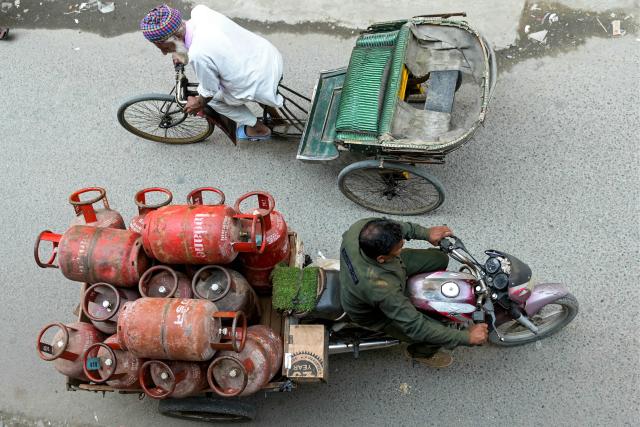 A delivery man transports liquid petroleum gas (LPG) cylinders in Amritsar on March 24, 2026. Two more Indian-flagged tankers carrying LPG passed through the Strait of Hormuz on March 23, India's shipping ministry said, marking a fresh set of exceptions in the chokepoint disrupted by the Middle East war. (Photo by Narinder NANU / AFP)