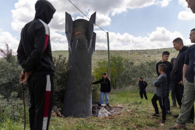 Palestinian men and children gather at an Iranian missile fragment that landed in the Israeli-occupied West Bank village of Hares on March 24, 2026. Since the United States and Israel unleashed strikes on Iran on February 28, war has spread across the Middle East, with casualties reported in countries across the region. (Photo by Ilia YEFIMOVICH / AFP)