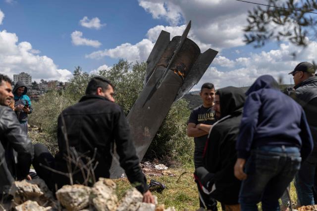 Palestinian men gather at an Iranian missile remnant that landed in the Israeli-occupied West Bank village of Hares on March 24, 2026. Since the United States and Israel unleashed strikes on Iran on February 28, war has spread across the Middle East, with casualties reported in countries across the region. (Photo by Ilia YEFIMOVICH / AFP) / 