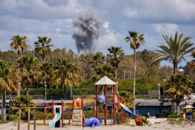 TOPSHOT - A playground stands empty as smoke rises in the distance from the site of an Israeli airstrike that targeted the outskirts of the southern city of Tyre on March 24, 2026. Lebanon was pulled into the Middle East war when Iran-backed Hezbollah began firing rockets into Israel on March 2 to avenge the killing of Iran's supreme leader Ayatollah Ali Khamenei. Israel has since launched strikes across Lebanon, killing at least 1,039 people and displacing more than a million others, and sent ground troops into the country's south. (Photo by Dimitar DILKOFF / AFP)