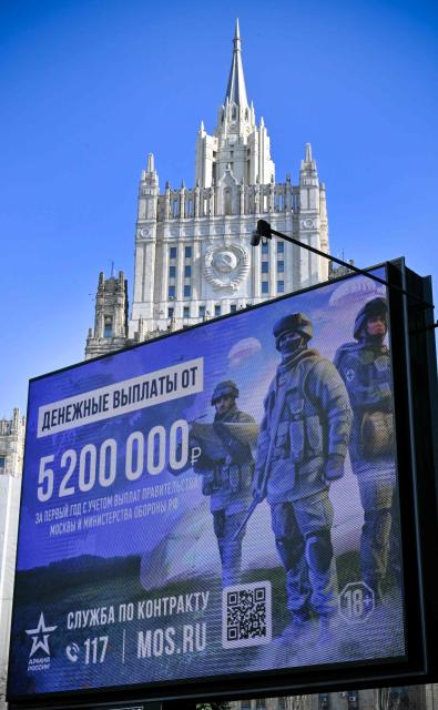 A billboard promoting contract army service and reading "5 200 000 rubles for the first year of the contract" (about USD 63 500) is seen in front of Russia's Foreign Ministry building in western Moscow on March 24, 2026. A barrage of Russian missiles and drones killed five people and wounded more than two dozen across Ukraine on Tuesday in the largest attack in weeks, as well as the Russian town of Belgorod located about 40 kilometers from the border, the large city of 320,000 inhabitants is under fire from missiles and drones launched by Kyiv, which claims to be primarily targeting energy and military infrastructure. Civilians are frequently killed and wounded. (Photo by Alexander NEMENOV / AFP)
