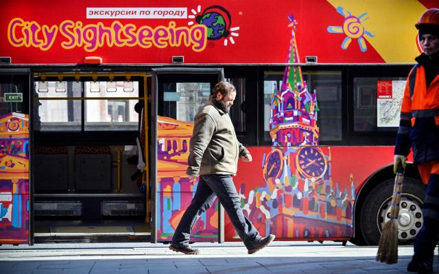 A man walks past a touristic bus at the touristic Arbat street in downtown Moscow on March 24, 2026. (Photo by Alexander NEMENOV / AFP)