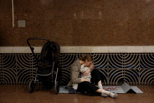A woman with a child takes shelter at a metro station during an air strike alarm in Kyiv on March 24, 2026, amid the Russian invasion of Ukraine. (Photo by Tetiana DZHAFAROVA / AFP)
