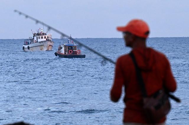 A man fishes as the vessel Maguro, arriving from Mexico with humanitarian aid as part of the Nuestra America convoy, docks at the port of Havana on March 24, 2026. (Photo by YAMIL LAGE / AFP)