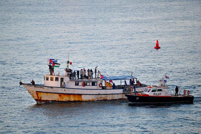 Activists wave Cuban and Palestinian flags as the vessel Maguro, arriving from Mexico with humanitarian aid as part of the Nuestra America convoy, docks at the port of Havana on March 24, 2026. (Photo by ADALBERTO ROQUE / AFP)