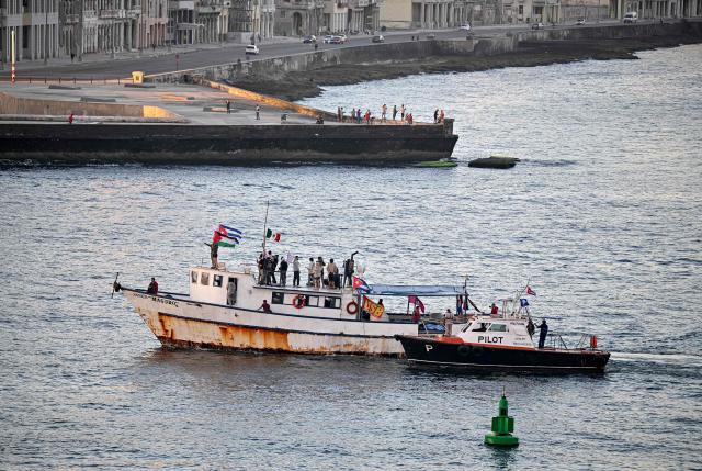 Activists wave Cuban and Palestinian flags as the vessel Maguro, arriving from Mexico with humanitarian aid as part of the Nuestra America convoy, docks at the port of Havana on March 24, 2026. (Photo by ADALBERTO ROQUE / AFP)