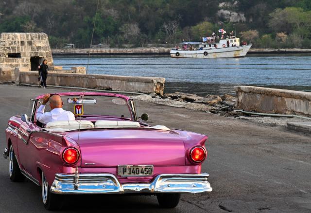 A man drives an old convertible car as the vessel Maguro, arriving from Mexico with humanitarian aid as part of the Nuestra America convoy, docks at the port of Havana on March 24, 2026. (Photo by YAMIL LAGE / AFP)
