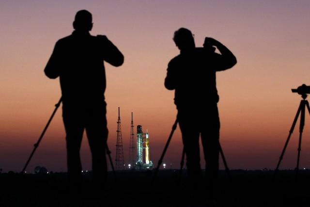 News media observe NASA's Artemis II Space Launch System (SLS) rocket and Orion spacecraft before sunrise at Launch Pad 39B at the Kennedy Space Center in Cape Canaveral, Florida on March 24, 2026. NASA on March 19 began returning its towering SLS rocket and Orion spacecraft to its Florida launch pad ahead of a planned flyby of the Moon, after completing necessary repairs. The next launch window opens on April 1. (Photo by Gregg Newton / AFP)