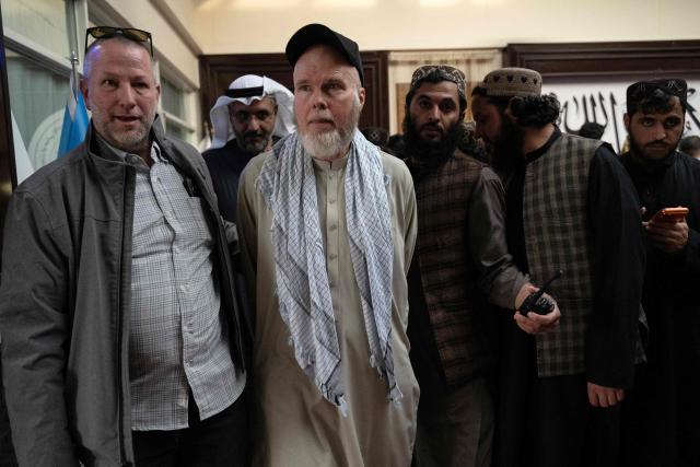 Taliban security personnel escort US citizen Dennis Coyle (C) toward a chartered aircraft at the airport in Kabul on March 24, 2026 after his release by the Taliban. Afghanistan's Taliban government announced on March 24 that it was freeing a US national who had been detained for more than a year. The foreign ministry said the family of linguist and researcher Dennis Coyle had written to the supreme leader of Afghanistan, requesting his release for Eid. (Photo by Wakil KOHSAR / AFP)