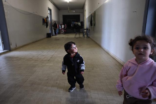 A displaced Lebanese toddler walks along a corridor inside a public school turned into a shelter in the town of Dekwaneh, north of Beirut on March 24, 2026. Lebanon was pulled into the Middle East war when the Tehran-backed Hezbollah militant group began firing rockets into Israel on March 2 to avenge the killing of Iran's supreme leader on February 28 by the US and Israel. Israel has since launched strikes across Lebanon, killing at least 1,039 people and displacing more than a million others in more than three weeks of fighting. It has also sent ground troops into the country's south. (Photo by Anwar AMRO / AFP)