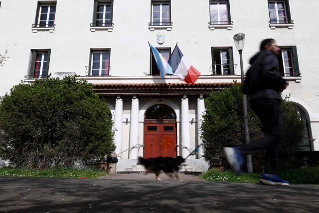 A person runs with a dog past the "Fondation Argentine" (Argentine foundation) at the Cite Internationale Universitaire in paris, on March 24, 2026. (Photo by Kenzo TRIBOUILLARD / AFP)