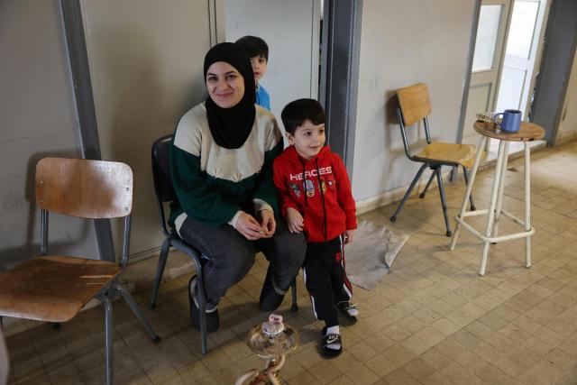 A displaced woman sits with her children at a corridor inside a public school turned into a shelter in the town of Dekwaneh, north of Beirut on March 24, 2026. Lebanon was pulled into the Middle East war when the Tehran-backed Hezbollah militant group began firing rockets into Israel on March 2 to avenge the killing of Iran's supreme leader on February 28 by the US and Israel. Israel has since launched strikes across Lebanon, killing at least 1,039 people and displacing more than a million others in more than three weeks of fighting. It has also sent ground troops into the country's south. (Photo by Anwar AMRO / AFP)