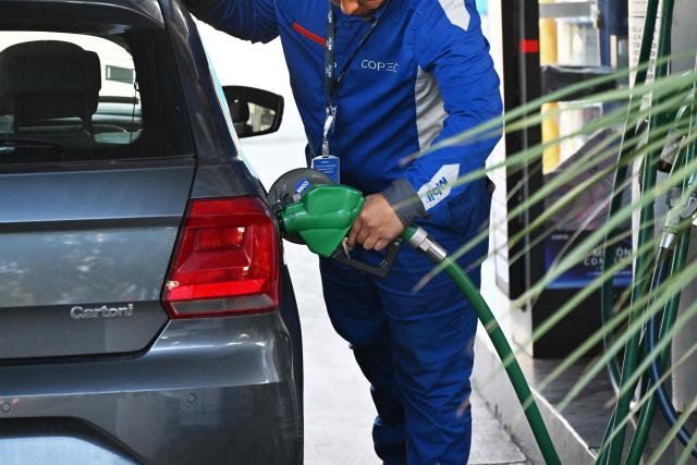 A worker fuels a vehicle at a gas station in Santiago on March 24, 2026. Chile's new government announced on March 23 a historic increase of nearly half a dollar per liter in fuel prices, after carrying out a major adjustment to a state mechanism designed to cushion volatility in international prices. (Photo by Rodrigo ARANGUA / AFP)