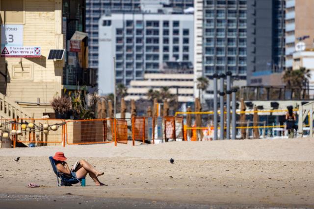 A woman reads a book on a largely empty beach in Tel Aviv on March 24, 2026. Iran fired a fresh broadside of missiles at Israel on March 24, causing damage and injuries in Tel Aviv, as uncertainty swirled over possible talks to end the three-week Middle East war. (Photo by Odd ANDERSEN / AFP) / 