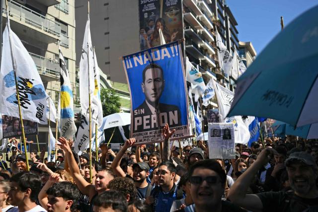 Demonstrators with a sign depicting former Argentinian President (1946-1955 and 1973-1974) Juan Domingo Peron, take part in a march to Plaza de Mayo aquare in Buenos Aires on March 24, 2026, on the 50th anniversary of the beginning of the last military dictatorship. In Argentina, March 24th is a day of mourning, marches and political disputes. Fifty years on from the coup detat, thousands of people are taking to the streets again to commemorate the victims of a dictatorship that the government of far-right leader Javier Milei is seeking to rewrite. (Photo by Luis ROBAYO / AFP)