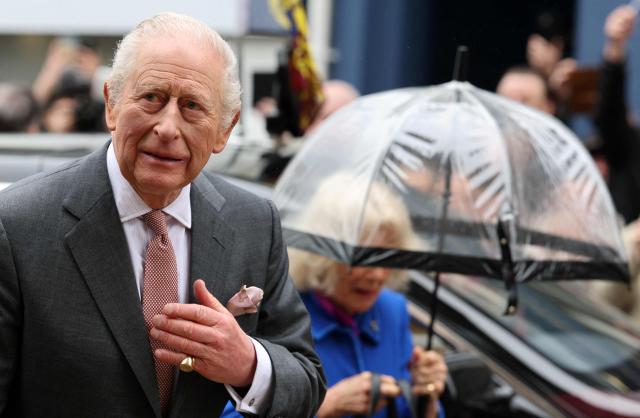 Britain's Queen Camilla shelters from the rain beneath an umbrella as she and Britain's King Charles III arrive to visit  Holy Trinity Church in St Austell, south-west England on March 24, 2026. (Photo by Adrian Dennis / POOL / AFP)