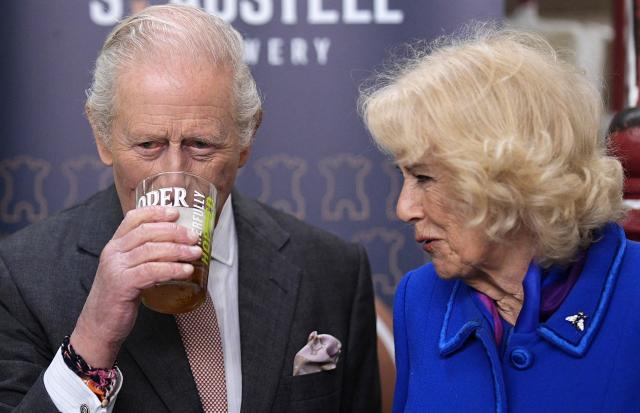 Britain's Queen Camilla reacts as she stands with Britain's King Charles III, as he tastes a pint of St Austell Brewery's Proper Job IPA 0.5% that he pulled, during a visit to the The Market Hall in St Austell, south-west England on March 24, 2026. (Photo by Aaron Chown / POOL / AFP)