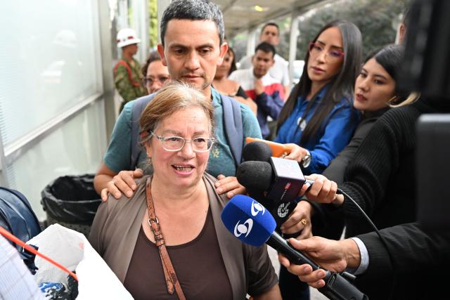 Marina, mother of Colombian soldier German Suarez - who survived a crash of the Air Force Hercules during takeoff in Puerto Leguizamo, near the southern border with Ecuador on March 23, 2026 - is surrounded by the press as she enters the Military Hospital in Bogota, on March 24, 2026. Colombia's military said on March 23 that about 80 troops were believed to be dead after a transport plane crash in the south of the country. (Photo by Daniel MUNOZ / AFP)