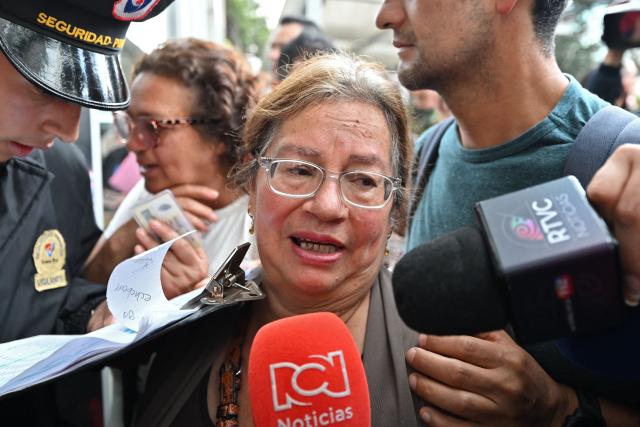 Marina, mother of Colombian soldier German Suarez - who survived a crash of the Air Force Hercules during takeoff in Puerto Leguizamo, near the southern border with Ecuador on March 23, 2026 - is surrounded by the press as she enters the Military Hospital in Bogota, on March 24, 2026. Colombia's military said on March 23 that about 80 troops were believed to be dead after a transport plane crash in the south of the country. (Photo by Daniel MUNOZ / AFP)