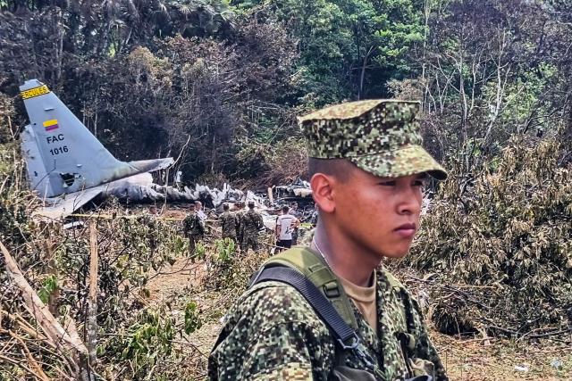 A soldier stands guard in front of the wreckage of the Air Force Hercules that crashed during takeoff in Puerto Leguizamo, Colombia, near the southern border with Ecuador, on March 24, 2026. A Colombian military plane carrying 125 soldiers and crew members crashed on takeoff early on March 23, killing at least 66 people and injuring dozens more, officials said. (Photo by daniel ortiz / AFP)