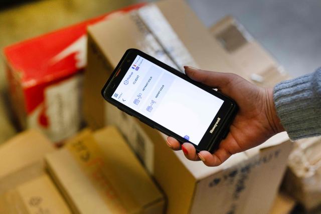 This photograph shows a person holding a device to check parcels for the Pickup mailing service in Quimper, western France, on March 24, 2026. (Photo by Fred TANNEAU / AFP)