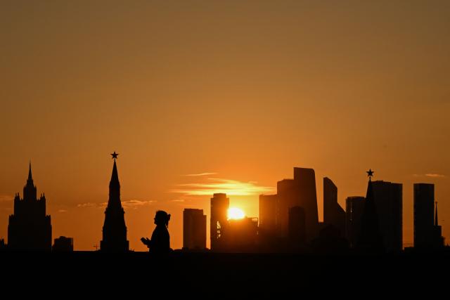 A woman walks over Moskvoretsky bridge as the sun sets over a panorama of Moscow in the background, in central Moscow on March 24, 2026. (Photo by Igor IVANKO / AFP)