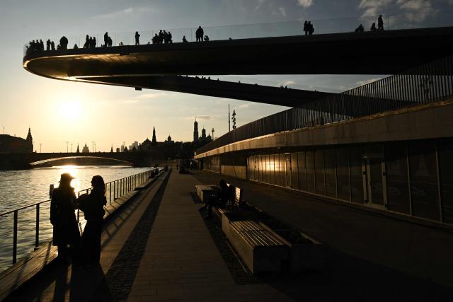 People relax on the Kremlevskaya embankment in view of the Kremlin in the background, in central Moscow on March 24, 2026. (Photo by Igor IVANKO / AFP)