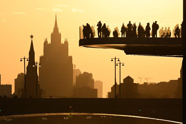 TOPSHOT - People walk on the Paryashiy bridge, also known as the floating bridge, with a panorama of Moscow in the background, in central Moscow on March 24, 2026. (Photo by Igor IVANKO / AFP)