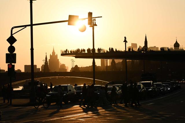 People cross Kremlevskaya embankment at sunset in central Moscow on March 24, 2026. (Photo by Igor IVANKO / AFP)