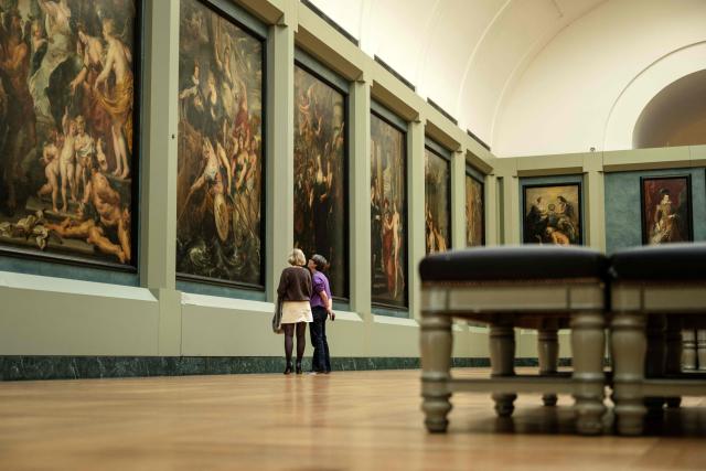 Employees look at paintings in The Medicis Gallery, in which are displayed 24 paintings by Flemish artist Peter Paul Rubens constituting the 'Marie de Medici Cycle', before their restoration, at Musee du Louvre in Paris on March 24, 2026. The Louvre has unveiled the details of an “exceptional operation” to restore the 24 paintings of the “Marie de’ Medici Cycle,” painted in the early 17th century by Rubens, one of the masters of Flemish painting. A call for tenders is underway to find two teams of restorers who will work simultaneously, starting in the autumn, on a project expected to last four years. (Photo by Blanca CRUZ / AFP)