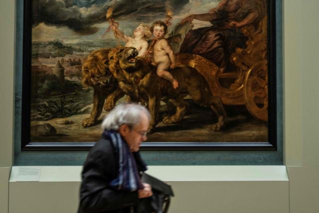 An employee walks past a painting in The Medicis Gallery, in which are displayed 24 paintings by Flemish artist Peter Paul Rubens constituting the 'Marie de Medici Cycle', before their restoration, at Musee du Louvre in Paris on March 24, 2026. The Louvre has unveiled the details of an “exceptional operation” to restore the 24 paintings of the “Marie de’ Medici Cycle,” painted in the early 17th century by Rubens, one of the masters of Flemish painting. A call for tenders is underway to find two teams of restorers who will work simultaneously, starting in the autumn, on a project expected to last four years. (Photo by Blanca CRUZ / AFP)