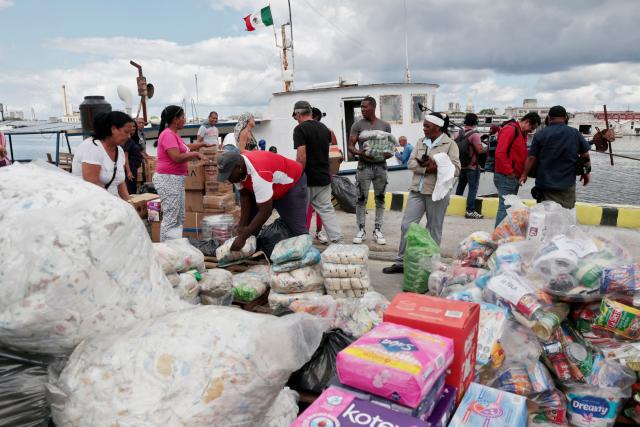 Activists of the NuestraAmerica Convoy and Cuban officials unload humanitarian aid from the vessel Maguro -- symbolically renamed "Granma 2.0" as a tribute to the yacht used by Fidel Castro's guerrilla fighters to launch their revolution in 1956 -- at Havana port on March 24, 2026. The first boat of a flotilla carrying medical supplies, food and solar panels reached Cuba on March 24, 2026 to aid the island as a US fuel blockade deepens its energy crisis. The Maguro shrimp fishing boat docked in Havana three days later than hoped after battling strong winds, currents and a pesky battery, with two other ships due to follow. (Photo by JORGE LUIS BANOS / POOL / AFP)