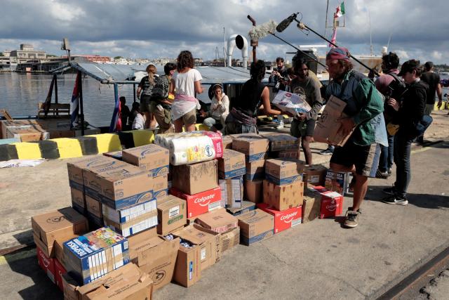Activists of the NuestraAmerica Convoy and Cuban officials unload humanitarian aid from the vessel Maguro -- symbolically renamed "Granma 2.0" as a tribute to the yacht used by Fidel Castro's guerrilla fighters to launch their revolution in 1956 -- at Havana port on March 24, 2026. The first boat of a flotilla carrying medical supplies, food and solar panels reached Cuba on March 24, 2026 to aid the island as a US fuel blockade deepens its energy crisis. The Maguro shrimp fishing boat docked in Havana three days later than hoped after battling strong winds, currents and a pesky battery, with two other ships due to follow. (Photo by JORGE LUIS BANOS / POOL / AFP)