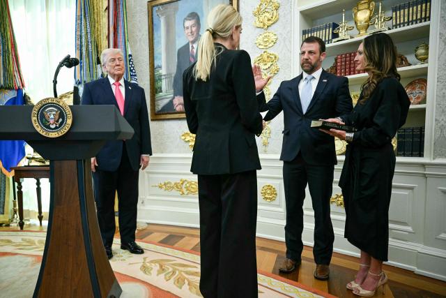 US President Donald Trump (L) looks on as Attorney General Pam Bondi swears in the new Secretary of Homeland Security Markwayne Mullin, alongside Mullin's wife Christine Mullin, in the Oval Office of the White House in Washington, DC, on March 24, 2026. The US Senate on Monday confirmed Mullin as the new chief of the Department of Homeland Security (DHS), the agency reeling from a partial government shutdown as it works to enforce President Donald Trump's immigration crackdown. (Photo by Jim WATSON / AFP)