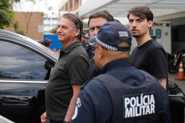 (FILES) Former Brazilian President (2019-2022) Jair Bolsonaro (L) leaves the DF Star hospital accompanied by his son Jair Renan (R) in Brasilia on September 14, 2025, after undergoing a series of medical examinations, as he remains under house arrest. A Brazilian Supreme Court judge authorized on March 24, 2026, former President Jair Bolsonaro to serve his sentence under “humanitarian” house arrest as soon as he is discharged from the hospital, where he has been admitted for 11 days for pneumonia. (Photo by Sergio Lima / AFP)