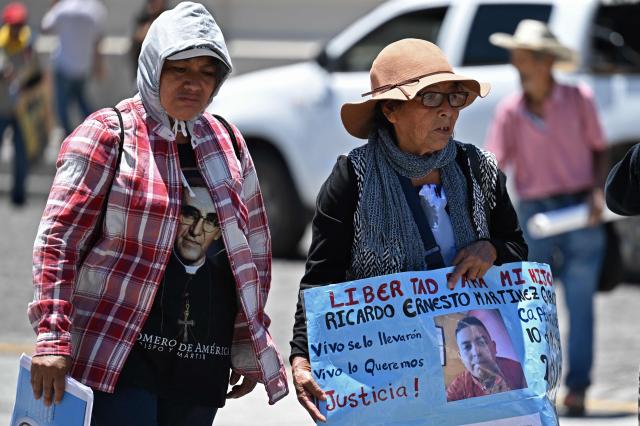 A woman holds a sign demanding her son's freedom during a protest against the emergency regime imposed by the government since March 2022, on the 46th anniversary of the assassination of Salvadoran Archbishop Oscar Arnulfo Romero (1917-1980) in San Salvador, on March 24, 2026. (Photo by Marvin RECINOS / AFP)