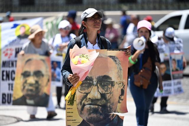 People protest against the emergency regime imposed by El Salvador's President Nayib Bukele's government since March 2022 during a march to commemorate the 46th anniversary of the assassination of Salvadoran Archbishop Oscar Arnulfo Romero (1917–1980) in San Salvador on March 24, 2026. (Photo by Marvin RECINOS / AFP)