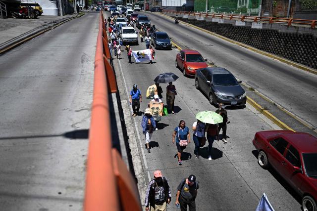 People walk along an avenue during a protest against the emergency regime imposed by the government since March 2022, on the 46th anniversary of the assassination of Salvadoran Archbishop Oscar Arnulfo Romero (1917-1980) in San Salvador, on March 24, 2026. (Photo by Marvin RECINOS / AFP)