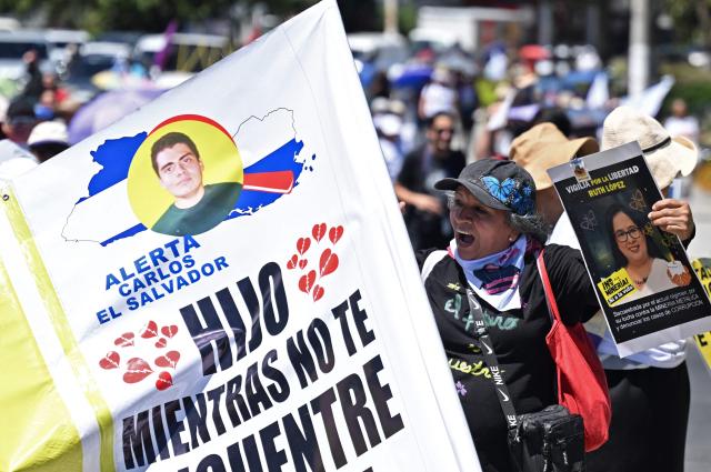A woman holds a portrait during a protest against the emergency regime imposed by the government since March 2022, on the 46th anniversary of the assassination of Salvadoran Archbishop Oscar Arnulfo Romero (1917-1980) in San Salvador, on March 24, 2026. (Photo by Marvin RECINOS / AFP)