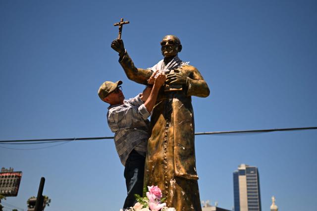 A demonstrator places a keffiyeh on a statue of Archbishop Oscar Arnulfo Romero during a march to commemorate the 46th anniversary of his assassination in San Salvador on March 24, 2026. (Photo by Marvin RECINOS / AFP)