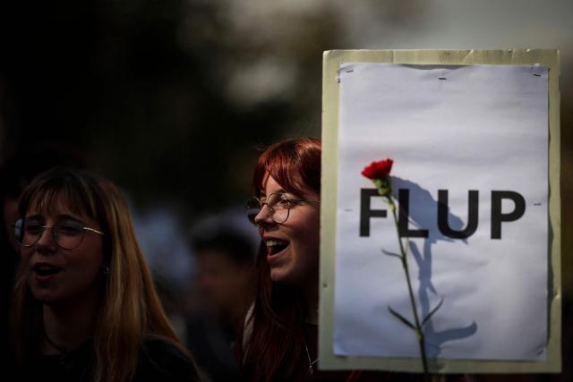 A student holds a poster and a red carnation (symbol of the 25th April Revolution) during a student demonstration to ask affordable housing, an end to tuition fees, and investment in social programs in Lisbon on March 24, 2026. University students across the country  demonstrate on “Student Day" to demand affordable housing, an end to tuition fees, and investment in social programs. (Photo by PATRICIA DE MELO MOREIRA / AFP)
