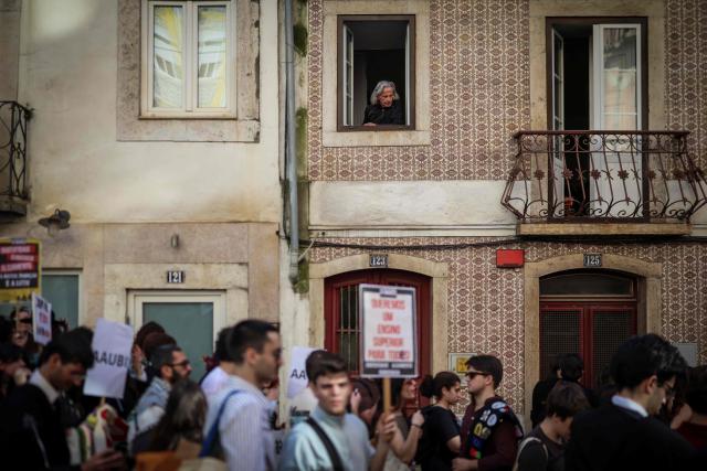 A man watches from his window as students demonstrate to ask affordable housing, an end to tuition fees, and investment in social programs in Lisbon on March 24, 2026. University students across the country  demonstrate on “Student Day" to demand affordable housing, an end to tuition fees, and investment in social programs. (Photo by PATRICIA DE MELO MOREIRA / AFP)