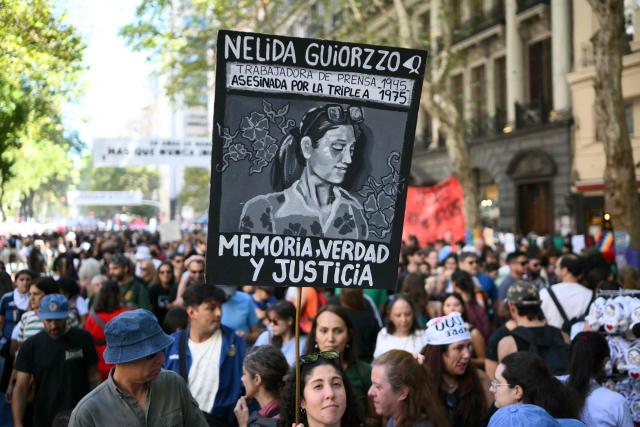 A woman holds up a sign depicting the disappeared person Nelida Guiorzzo during a march to Plaza de Mayo square in Buenos Aires on March 24, 2026, on the 50th anniversary of the beginning of the last military dictatorship. In Argentina, March 24th is a day of mourning, marches and political disputes. Fifty years on from the coup d’etat, thousands of people are taking to the streets again to commemorate the victims of a dictatorship that the government of far-right leader Javier Milei is seeking to rewrite. (Photo by Luis ROBAYO / AFP)